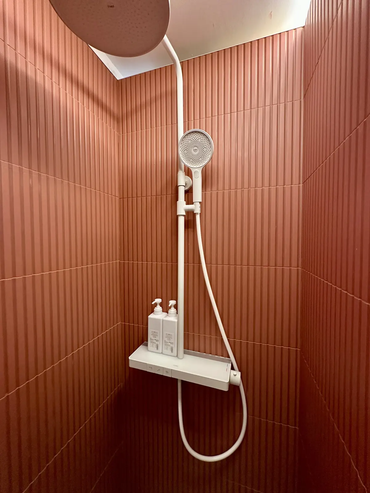 Douche en faïence cannelée terracotta dans une salle d'eau compacte